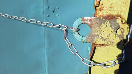 Rusty metal lock with chain on weathered blue background