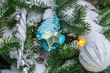 Christmas decorations on a snow-covered Christmas tree. Background of Christmas tree toys. Festive decorations on Christmas Eve. Winter holidays.