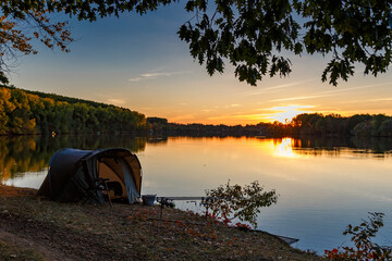 fishing adventures, carp fishing. angler, at sunset, is fishing with carpfishing technique. camping 