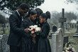 © Bonsales - Family African American dressed in black gathers at cemetery embracing and holding flowers while mourning loss at gravesite, showing deep grief and solidarity