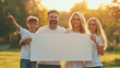 © Danimotions - Family celebrating a sunny afternoon in a park, holding a blank sign for fun activities and memories