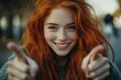 © Fotograf - A confident woman with bright red hair gives a thumbs up, conveying positivity and approval