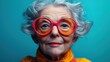 © Светлана Гуркова - Elderly woman with vibrant glasses and wild gray hair against a bright blue background, exuding personality and charm