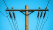 © arsyi_06 - A wooden utility pole with power lines against a blue sky.