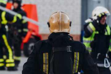 Group of fire men in uniform during fire fighting operation in the city streets, firefighters with the fire engine truck vehicle in the background, emergency and rescue, fire drill, exercise training