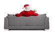 © Ljupco Smokovski - Rear view shot of Santa claus sitting on a sofa with a box of popcorn