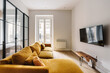 © Nibuya Qubik/Stocksy - Modern living room with a mustard yellow sofa