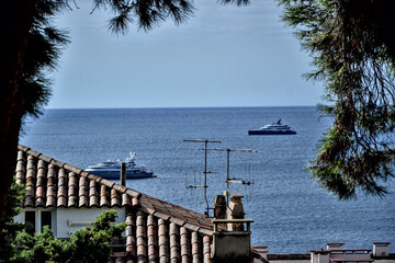 Cannes, France - September 7th 2024 : High view of the city. Focus on two boats on the sea, over a rooftop.