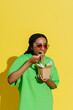 © Sergey Narevskih/Stocksy - Smiling woman eating takeout with chopsticks against yellow background