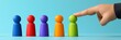 © StockUp - A green wooden figure is selected by a hand from a lineup of colorful figures, symbolizing choice and individuality.