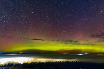 a vivid aurora borealis with striking red and green hues lights up the starry night sky above a town