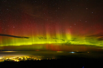 a vivid aurora borealis with striking red and green hues lights up the starry night sky above a town