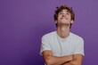 © NOORULHASSAN - Happy joyful smiling young man looking aside up thinking new opportunities, dreaming and feeling inspired, isolated on a purple background.