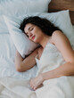 © Marija Savic/Stocksy - Beautiful Curly Haired Woman Sleeping Peacefully In Bed