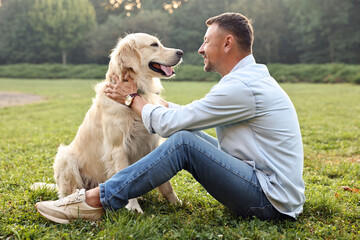 Wall Mural - Smiling man with cute Golden Retriever dog on spring day