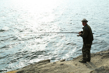 Wall Mural - Fisherman with rod fishing near lake at summer, back view