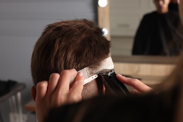 Wall Mural - Professional barber making stylish haircut in salon, closeup