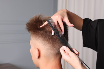 Canvas Print - Professional barber making stylish haircut in salon, closeup