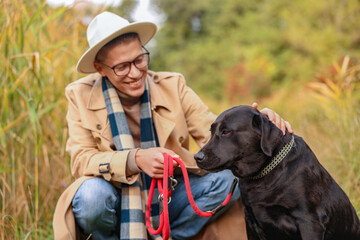 Canvas Print - Smiling man stroking cute dog outdoors on autumn day