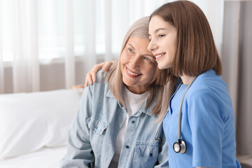 Wall Mural - Smiling healthcare worker supporting senior patient on bed indoors. Space for text