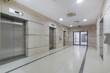 © alhim - Spacious lobby in an office building. Modern elevators with metal doors. The room is .decorated with light tiles.