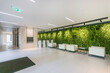 © alhim - Exclusive design of the lobby of the office center. White armchairs and tables against .the wall decorated with green plants.