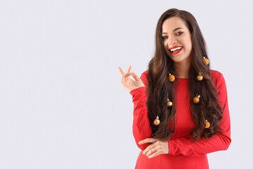 Poster - Beautiful young happy woman with Christmas balls in her hair on grey background