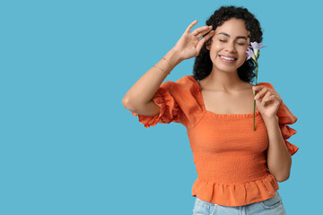 Wall Mural - Young African-American woman with beautiful flower on blue background. International Women's Day