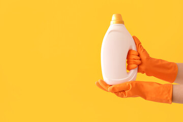 Wall Mural - Female hands in rubber gloves with laundry detergent on yellow background