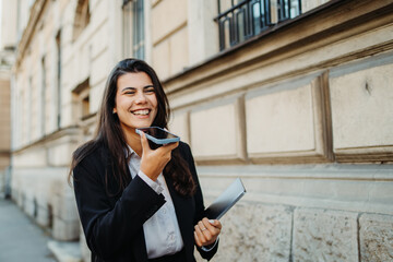 Young businesswoman sending voice message on smartphone on the street	
