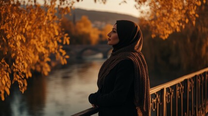 a hijabi woman standing on a bridge during sunset