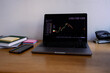 © Oleksii Syrotkin/Stocksy - Business graph of stock market on laptop on desk and office supplies