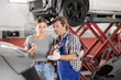 © JackF - Adult male mechanic advises young woman client on car repair in car service station