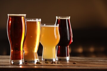 Poster - Glasses with different types of beer and pistachio nuts on wooden table indoors