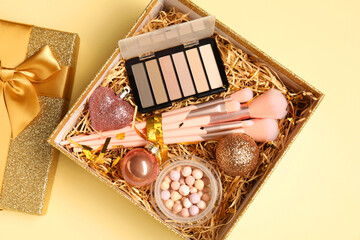 Wall Mural - Makeup brushes, blush and Christmas decor in box on yellow background, top view