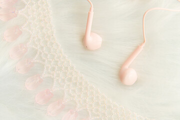 Wall Mural - Light pink and white pendant necklace with light pink earphones on a furry white background