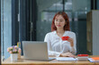 © Songsak C - Asian businesswoman sitting and holding a cup of coffee.
