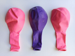 Two pink and one purple balloon. Deflated balloons are lying on the table. Toys for children. Background, space for text.