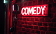 © Curioso.Photography - Microphone on stage with a neon comedy sign in the background.