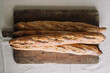 © Adrian Cotiga/Stocksy - Three artisanal baguettes on rustic wooden cutting board.