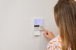 © Shava Cueva/Stocksy - Person adjusting a thermostat on a wall indoors with copyspace