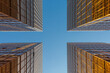 © Heng Yu/Stocksy - Upward view of modern glass buildings reflecting sunlight against blue