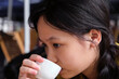 © ChaoShu Li/Stocksy - Closeup of an Asian girl drinking Chinese tea in an outdoor teahouse