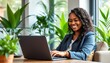 © OlScher - A professional woman working with a laptop in a bright office filled with plants