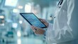 © สมเจตน์ หนูแก้ว - Doctor holding a digital tablet with medical data displayed on the screen