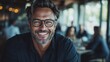 © Larisa AI - A man wearing glasses smiles warmly in a cozy modern interior, combining a sense of relaxation and happiness in an elegant and welcoming environment.