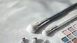 © Preecha - A stylish flat lay of various cosmetic brushes and palettes strategically placed on a textured fabric backdrop, with a warm light casting gentle shadows. The composition allows for ample copy space,