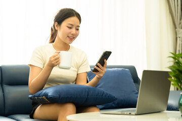 Wall Mural - Portrait of young Asian girl using laptop and drink coffee ,  at home