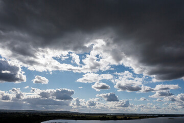 Clouds of different sizes in the sky, with sun rays shining through.