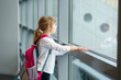 © Irina Schmidt - Little Girl at the Airport Waiting for Boarding at the Big Window. Cute Kid Stands at the Window against the Backdrop of Airplanes. Looking Forward to Leaving for a Family Summer Vacation